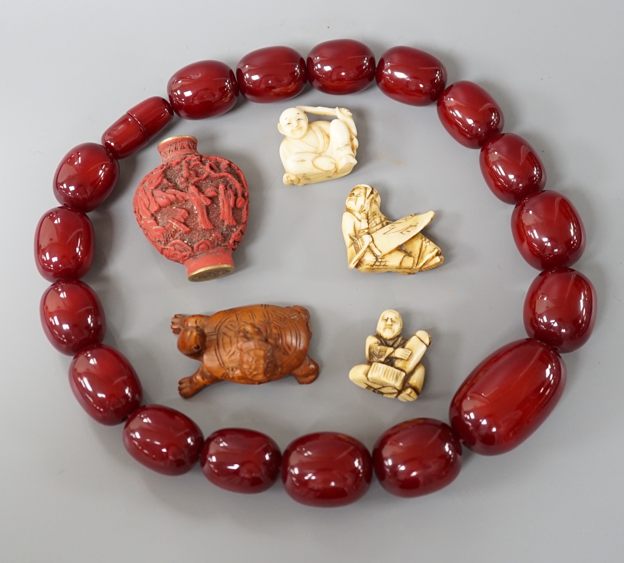 Assorted Chinese and Japanese Ivory and wood carvings, a scent bottle and a simulated cherry amber bead necklace, Necklace 52 cms long.